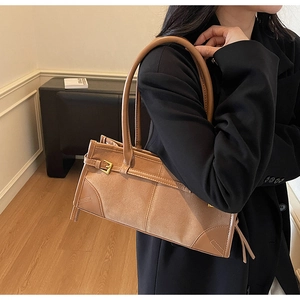 Close-up of stylish brown suede shoulder bag with metal buckle and long handle