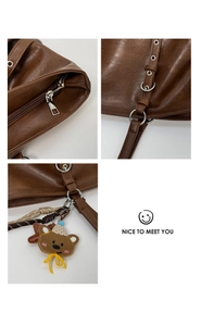 Detail of brown PU leather tote bag with silver zipper and cute teddy bear pendant