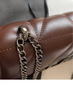 Macro detail of brown quilted leather texture and dark metallic chain hardware