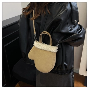 Detail of glove-shaped suede bag with white faux fur trim and adjustable shoulder strap