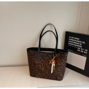 Macro shot of leopard print tote bag detailing textured fabric and beaded tassel charm