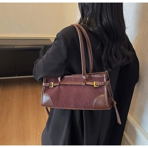 Detail of burgundy patchwork shoulder bag with suede texture and gold buckle