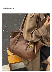Brown vintage leather tote bag with metal eyelets and a bear pendant on a model