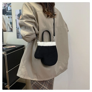 Model wearing a creative black plush glove shaped shoulder bag with white faux fur trim