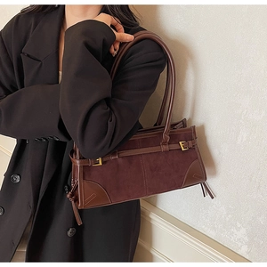 Detail of dark brown suede and leather patchwork tote with golden metal hardware
