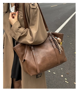 Detail of retro brown tote bag with metal eyelets and a cute bear charm on shoulder