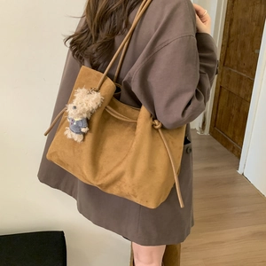 Detailed view of brown suede tote bag with drawstring side and cute bear keychain charm