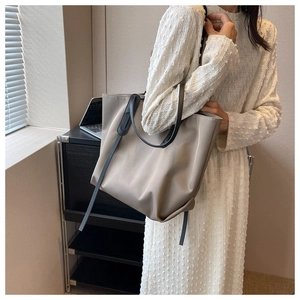 Détail d'un grand sac cabas kaki avec des lanières noires dans un décor de bureau