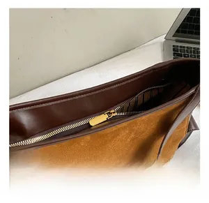 Close-up of golden zipper hardware and brown suede material on women's tote bag