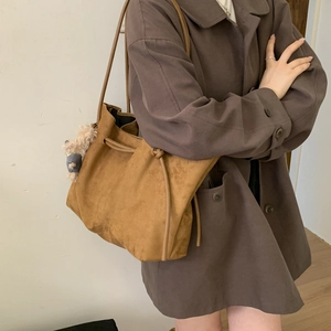 Close-up of brown suede tote bag featuring a drawstring closure and cute plush charm detail