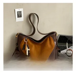 Detail of vintage suede hobo bag with tassel and wide shoulder strap in home setting