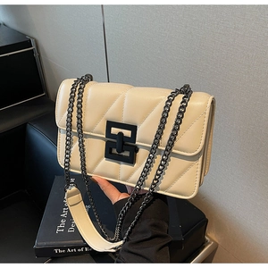 Detail of beige quilted flap bag with diamond stitching and chunky black chain strap