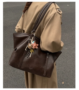 Detail of deep brown faux leather tote bag with shoulder strap and cute bear charm pendant