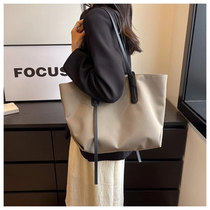 Vue latérale d'un sac cabas beige en tissu Oxford sur l'épaule d'un mannequin