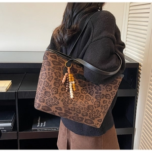 Detail of leopard print tote bag with black leather strap and colorful beaded charm