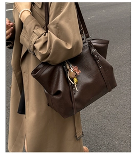 Detailed view of dark brown faux leather tote bag with a cute bear charm and adjustable strap