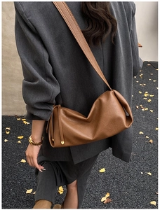 Détail d'un sac baguette en similicuir marron caramel avec pompon noué sur le côté