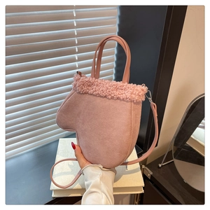 Detail of pink glove-shaped handbag featuring faux fur trim and adjustable strap
