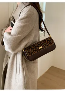 Detail of leopard print and brown leather shoulder bag worn over a beige wool coat