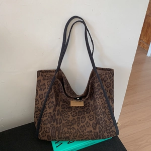 Close-up of leopard print tote bag fabric with leather label and black shoulder straps