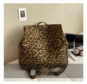 Detailed view of leopard print canvas backpack with red embroidery and metal magnetic closure
