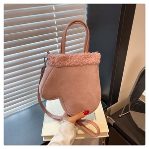 Detail of pink glove-shaped handbag with plush trim and soft faux suede texture