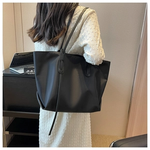 Gros plan d'un grand sac cabas noir en tissu Oxford porté par un mannequin au bureau