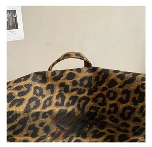 Detail of leopard print canvas tote bag with red cursive embroidery and sturdy handles