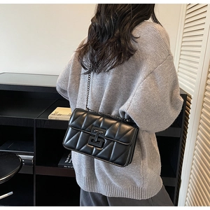 Detail showing the black quilted pattern and metal chain strap of the modern flap bag