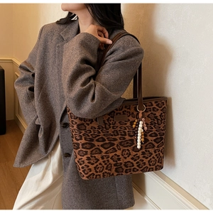Detail of leopard print canvas tote bag with brown leather trim and unique beaded charm