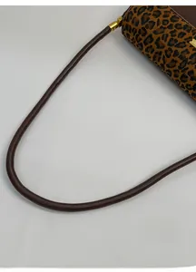 Detail of leopard print shoulder bag featuring premium brown leather handle and gold hardware