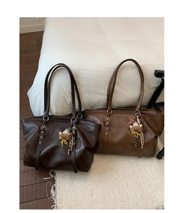 Close-up of leather tote bags with cute bear pendants and silver hardware details