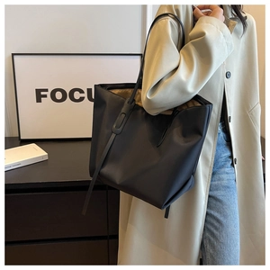 Vue détaillée d'un grand sac fourre-tout noir en tissu Oxford avec des poignées en cuir chic