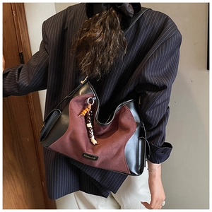 Detail of vintage burgundy suede hobo bag with beaded charm and leather strap