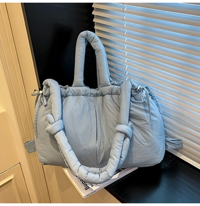 Detail of light blue quilted puffer tote with knotted handles and drawstring closure