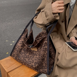 Outdoor lifestyle shot of a leopard print canvas tote bag on a wooden bench
