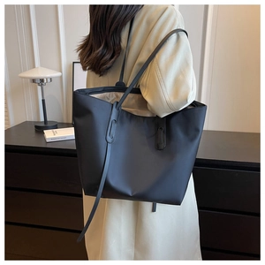 Vue de côté d'un grand sac fourre-tout noir en tissu Oxford porté par un mannequin