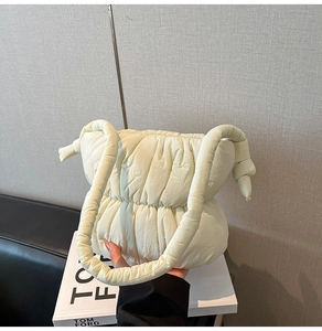 Detail of cream quilted puffer bag with knotted shoulder strap in a stylish setting