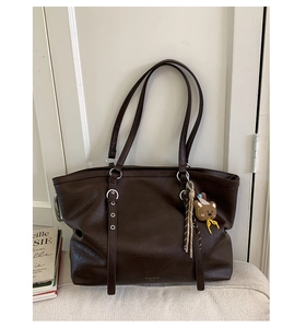 Detail of coffee brown leather tote bag with soft texture and cute bear charm pendant