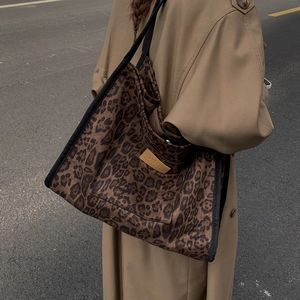 Detail view of large leopard print canvas tote bag with adjustable shoulder strap and tag