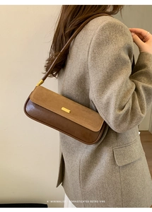 Detail showing two-tone leather texture and golden buckle on the underarm bag