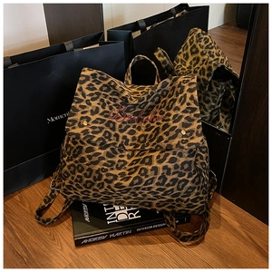Detail of leopard print canvas backpack with red embroidery and gold metal buckles