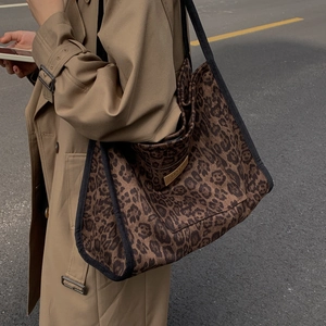 Detail of the leopard print tote bag with a gold metal logo plate and black straps
