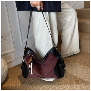 Close-up of hobo bag in black leather and burgundy suede with a beaded charm