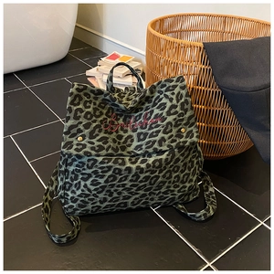 Detail of green leopard canvas backpack with red script embroidery and metal buckle
