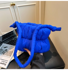 Detail of blue padded puffer bag featuring quilted texture and knotted shoulder strap