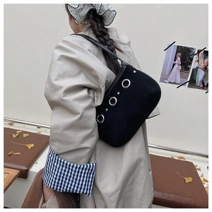 Detail of minimalist suede shoulder bag featuring large silver metal rings and rivets decor