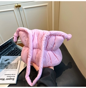 Close-up of pink puffy cloud bag with quilted texture and knotted shoulder strap detail