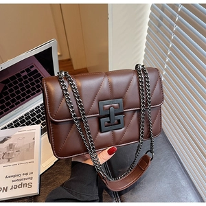 Detail of V-quilted brown leather crossbody bag with black geometric lock and chain strap