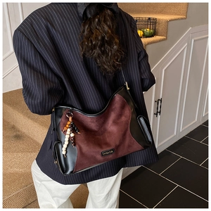 Detail of burgundy suede tote with beaded tassel and metallic logo on striped blazer